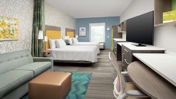Una habitación de hotel con una cama, un sofá, un escritorio y un televisor.