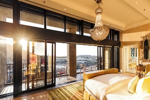 A spacious bedroom with a large bed, a chandelier, and a balcony with a view. - The Silo Hotel (Cape Town)