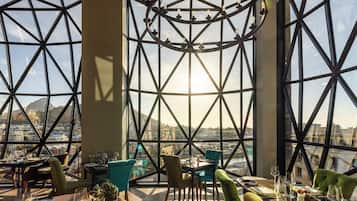 A restaurant with a modern interior, large windows, and a view of the cityscape.