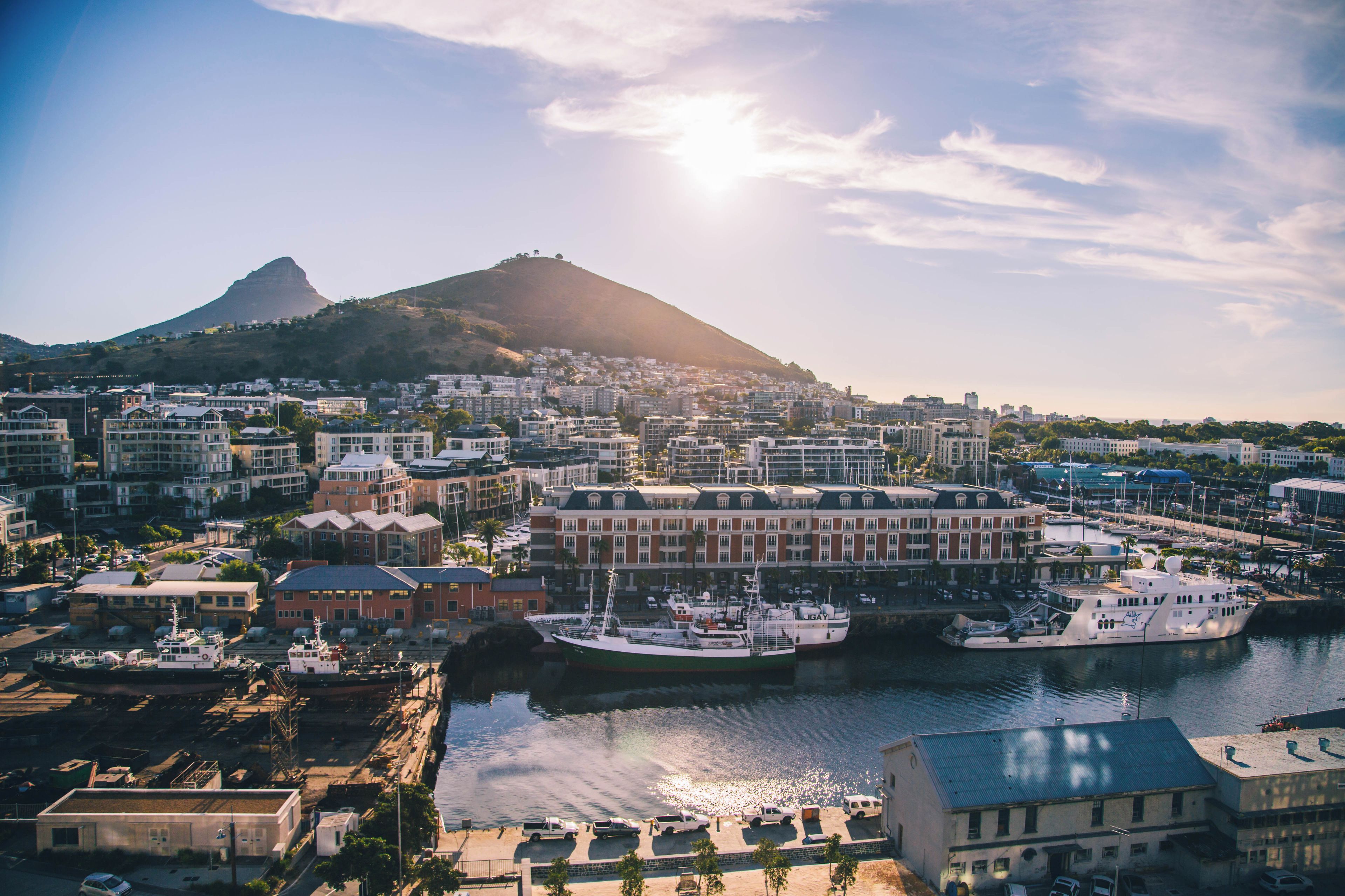 A coastal cityscape with a prominent hill, marina with boats, and a variety of buildings.