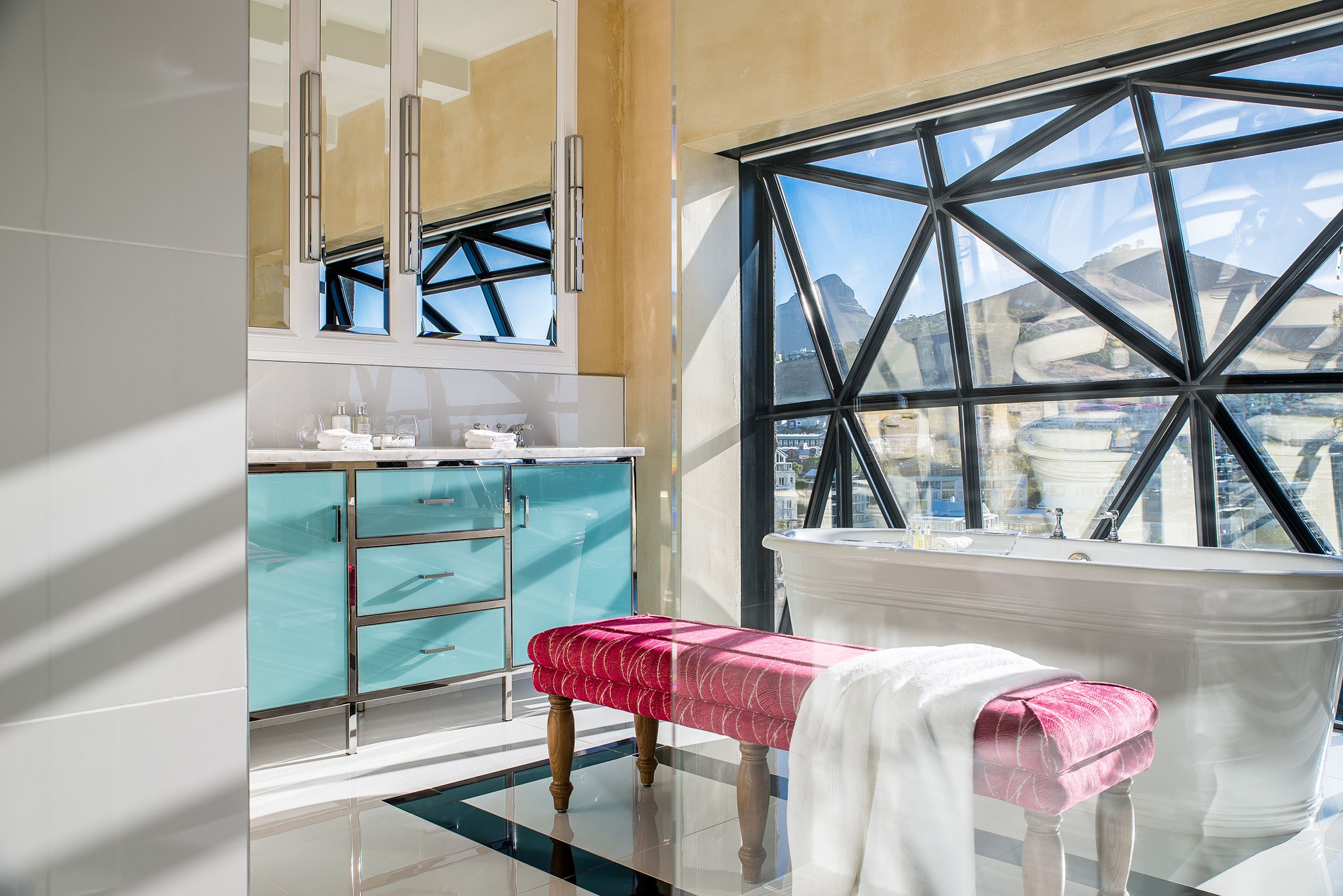 Un baño moderno con un ventanal grande, un banco y un tocador con espejo.