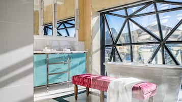 Un baño moderno con un ventanal grande, un banco y un tocador con espejo.