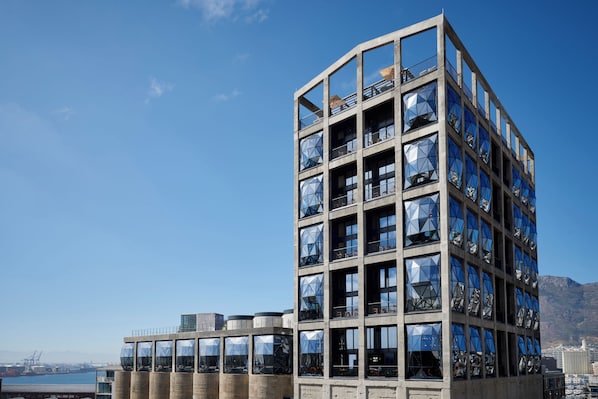 A high-rise building with multiple balconies and large windows reflecting the sky. - The Silo Hotel (Cape Town)