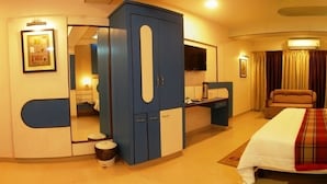 Habitación de hotel con cama, escritorio, silla, armario y televisión.