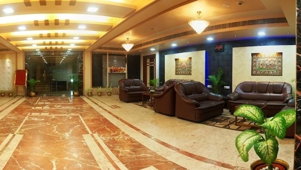 Un vestíbulo de hotel con mostrador de recepción, zona de estar y suelo de mármol.