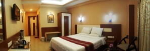 A hotel room with a bed, bedside tables, a TV, a wardrobe, and a bathroom visible through an open door. - Nayak Beach Resort (Puri)