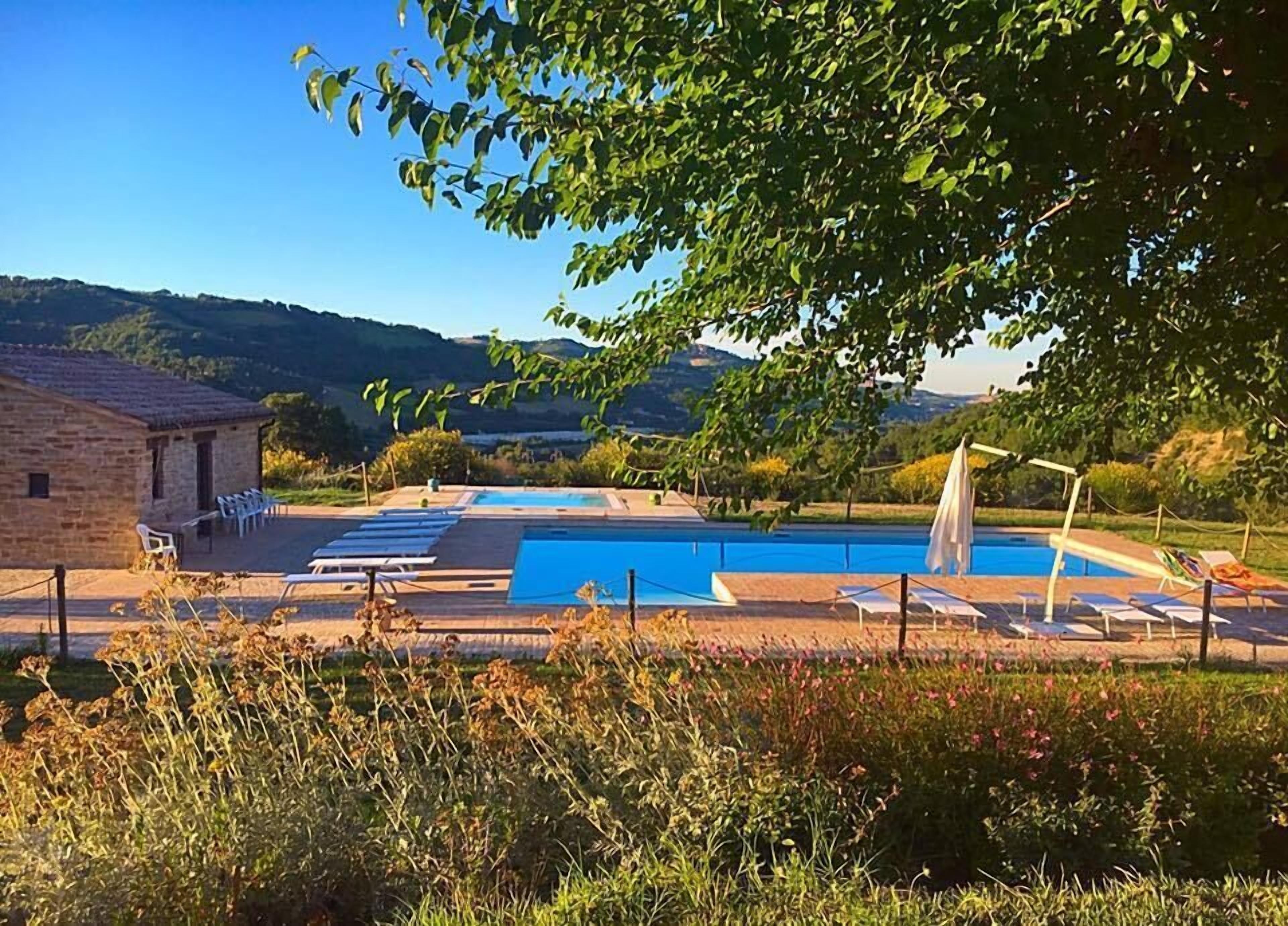 A pool area with multiple pools, lounge chairs, and a small building.