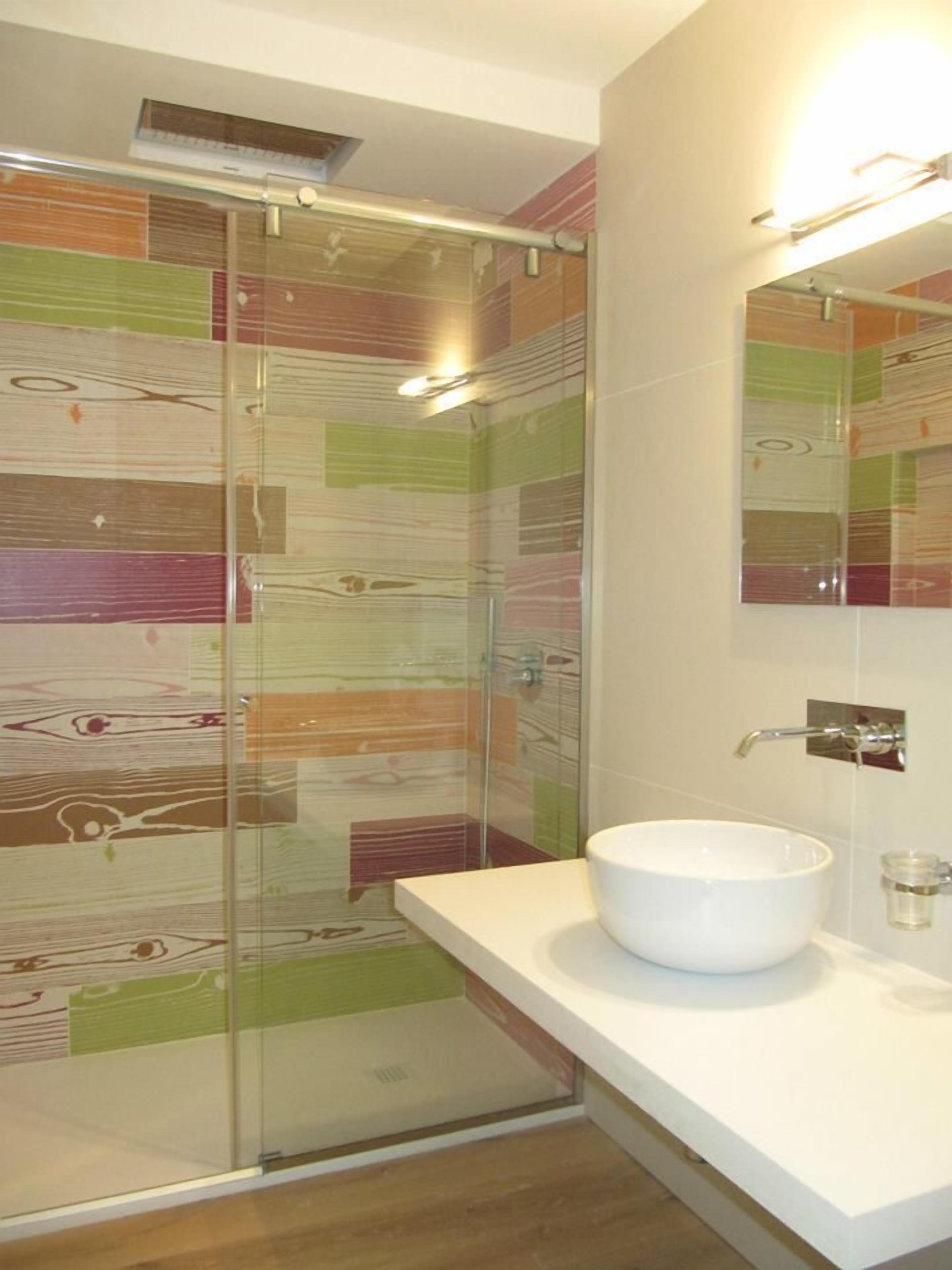 Une salle de bain moderne avec une douche à parois de verre, un lavabo blanc et un miroir.
