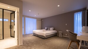 Ein modernes Hotelzimmer mit einem großen Bett, einem Schreibtisch und einem begehbaren Kleiderschrank.