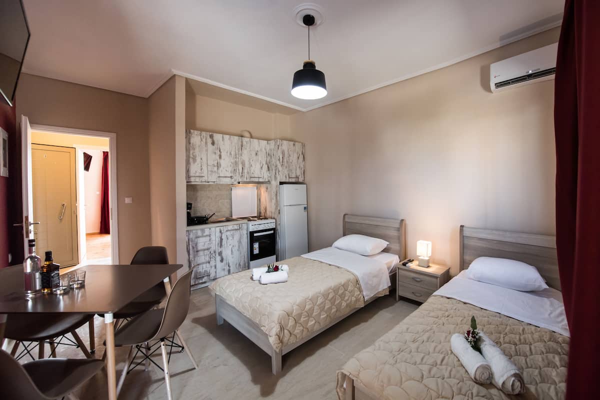 Ein Hotelzimmer mit zwei Betten, einem Essbereich, einer Küchenzeile und einem Badezimmer.