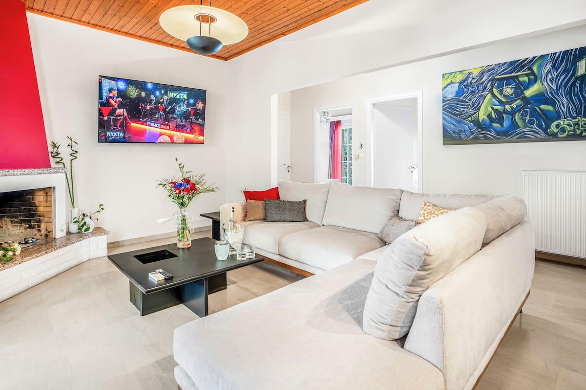 Ein modernes Wohnzimmer mit einem Ecksofa, einem Kamin, einem Flachbildfernseher und Kunstwerken an den Wänden.