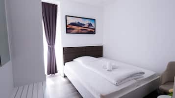 Una habitación de hotel moderna con una cama grande, un cabecero, un cuadro en la pared y una ventana con cortinas.