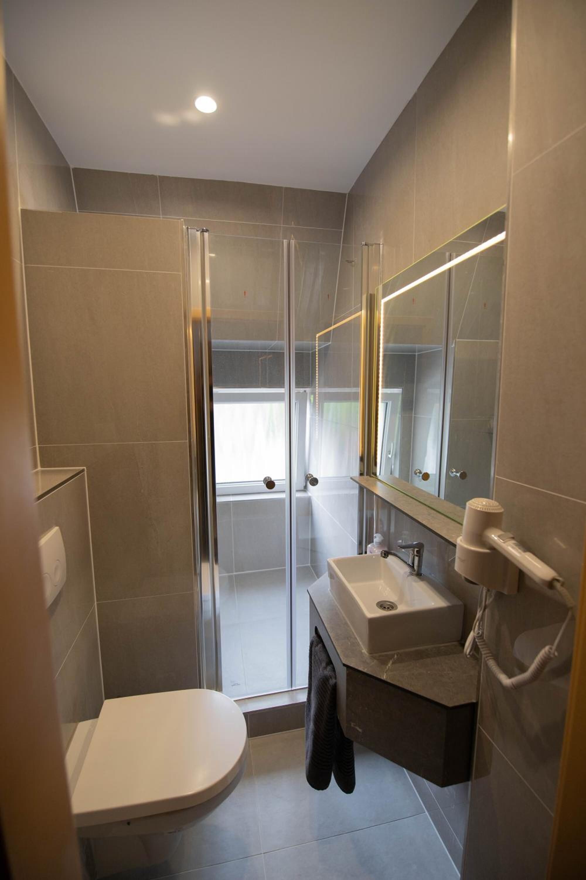 A modern bathroom with a glass shower enclosure, a white toilet, a sink with a mirror, and a towel rack.