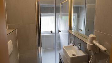 A modern bathroom with a glass shower enclosure, a white toilet, a sink with a mirror, and a towel rack.