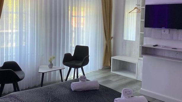 A modern hotel room with a large bed, a desk, a chair, and a television. - Heidepension (Bispingen)