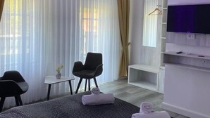 A modern hotel room with a large bed, a desk, a chair, and a television.