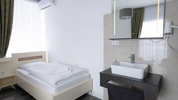 Une chambre d’hôtel moderne équipée d’un lit, d’une coiffeuse avec miroir et d’un appareil de climatisation.