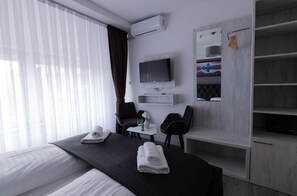 A hotel room with a bed, a desk, a chair, a TV, and a wardrobe.