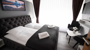 A hotel room with a large bed, a small desk, a chair, and a TV.
