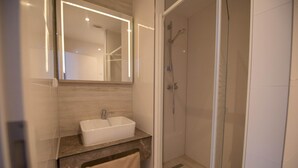 A modern bathroom with a glass shower enclosure, a double sink vanity, and a large mirror. - Heidepension (Bispingen)