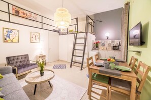 Um espaço compacto com quarto em mezanino, área de jantar e cozinha compacta.