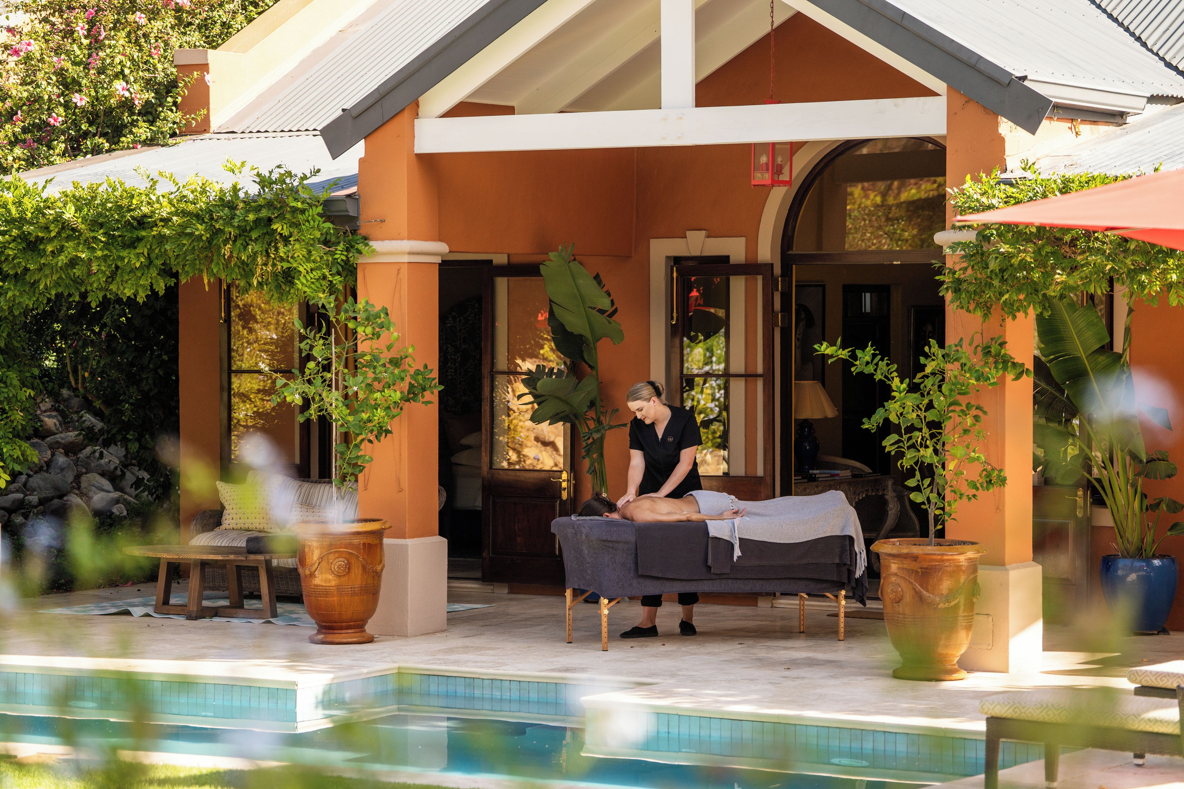 A spa area with a massage table, a massage therapist, and a pool.
