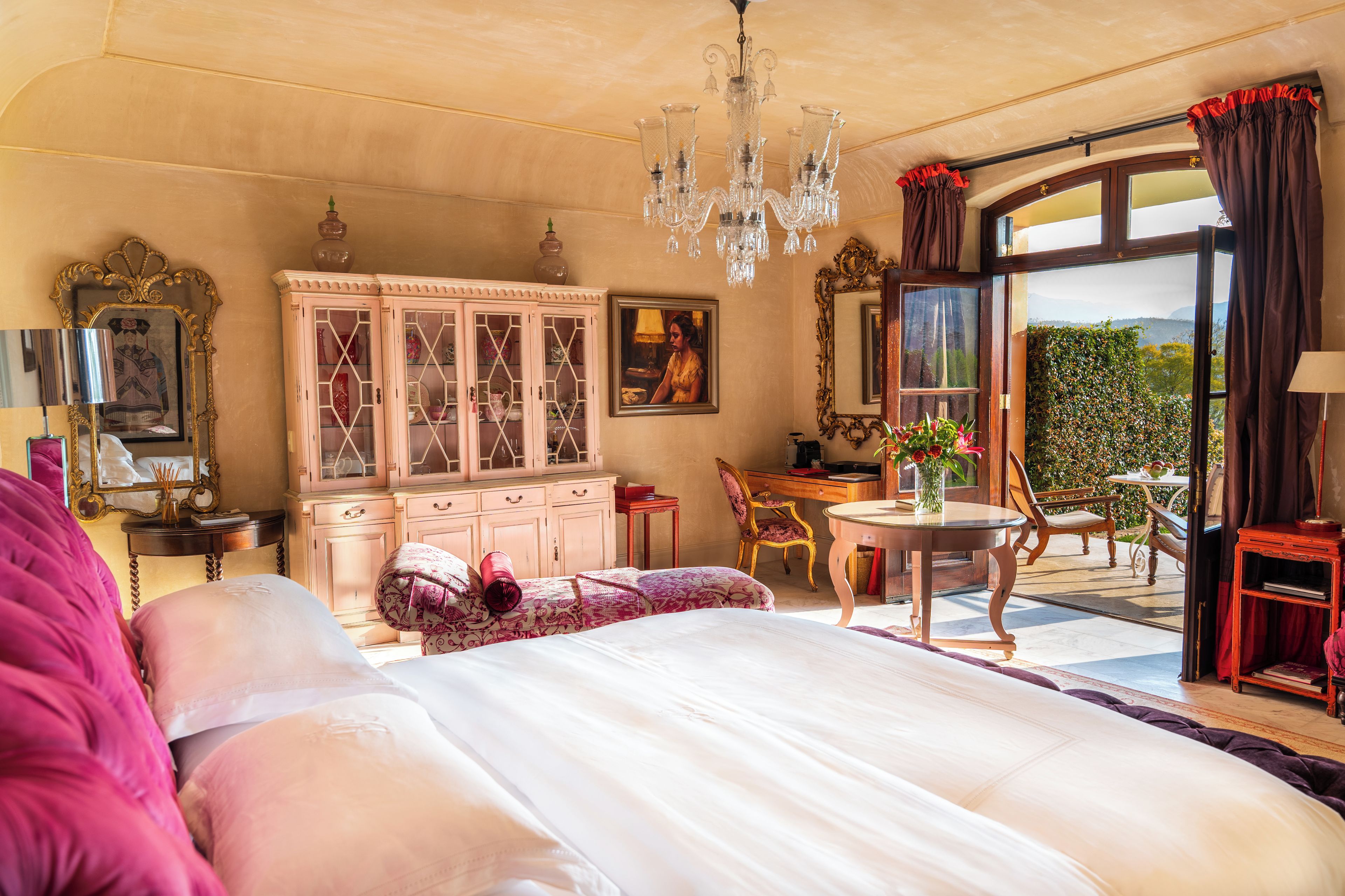 Une chambre spacieuse avec un grand lit, un bureau et une vue sur l’extérieur grâce à une porte vitrée.