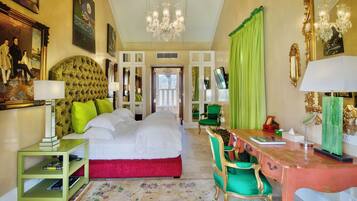 Une chambre d’hôtel avec un grand lit, un bureau avec une chaise, un miroir et un lustre.