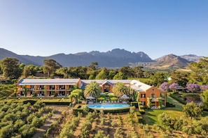 A large resort with multiple buildings, a swimming pool, and a view of mountains. - La Residence (Franschhoek)