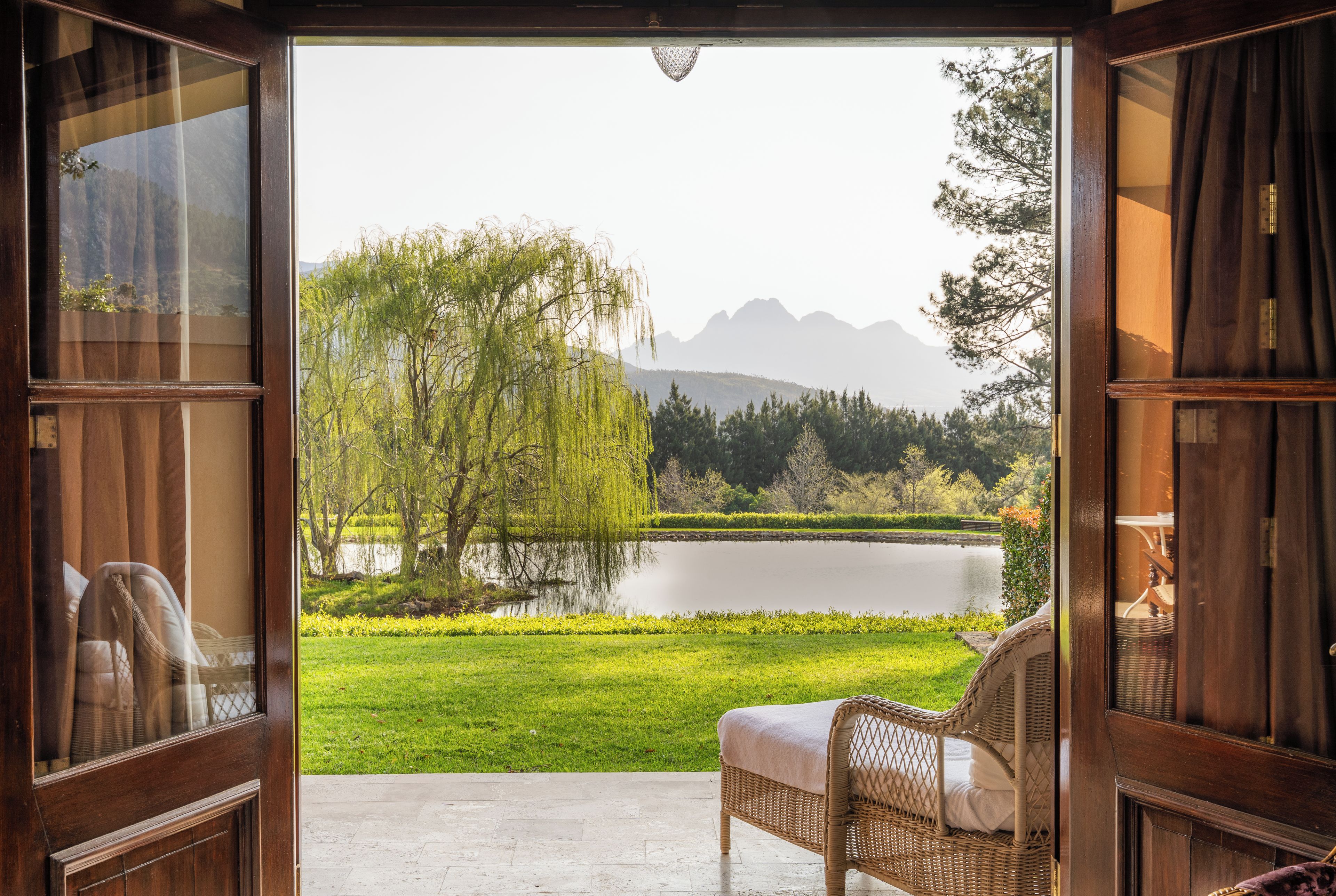 A room with a view of a lake, a chair, and a wooden door.