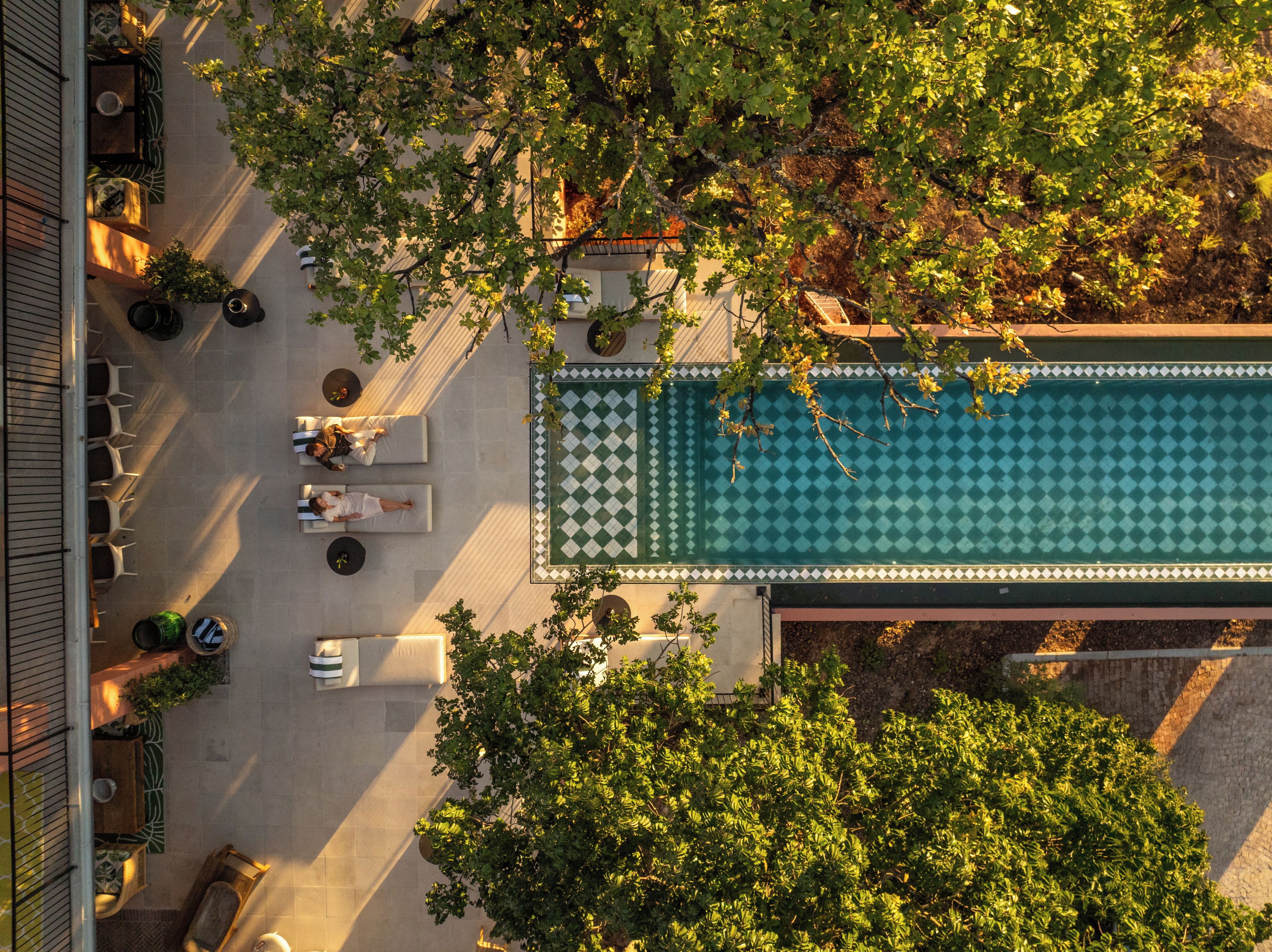 An aerial view of a rooftop pool area with lounge chairs and a checkered pool deck.