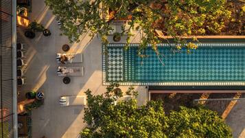 An aerial view of a rooftop pool area with lounge chairs and a checkered pool deck.