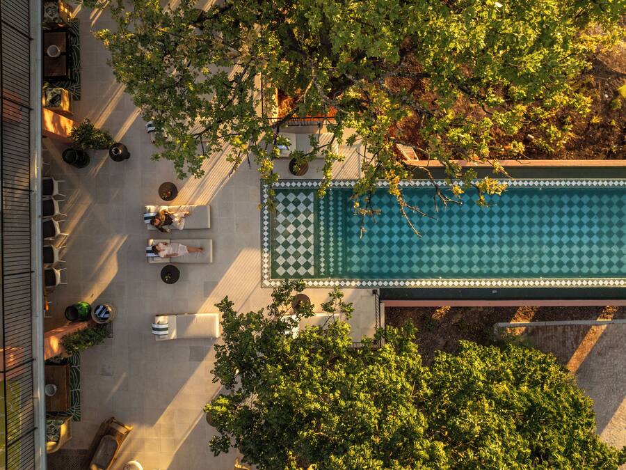 An aerial view of a rooftop pool area with lounge chairs and a checkered pool deck.