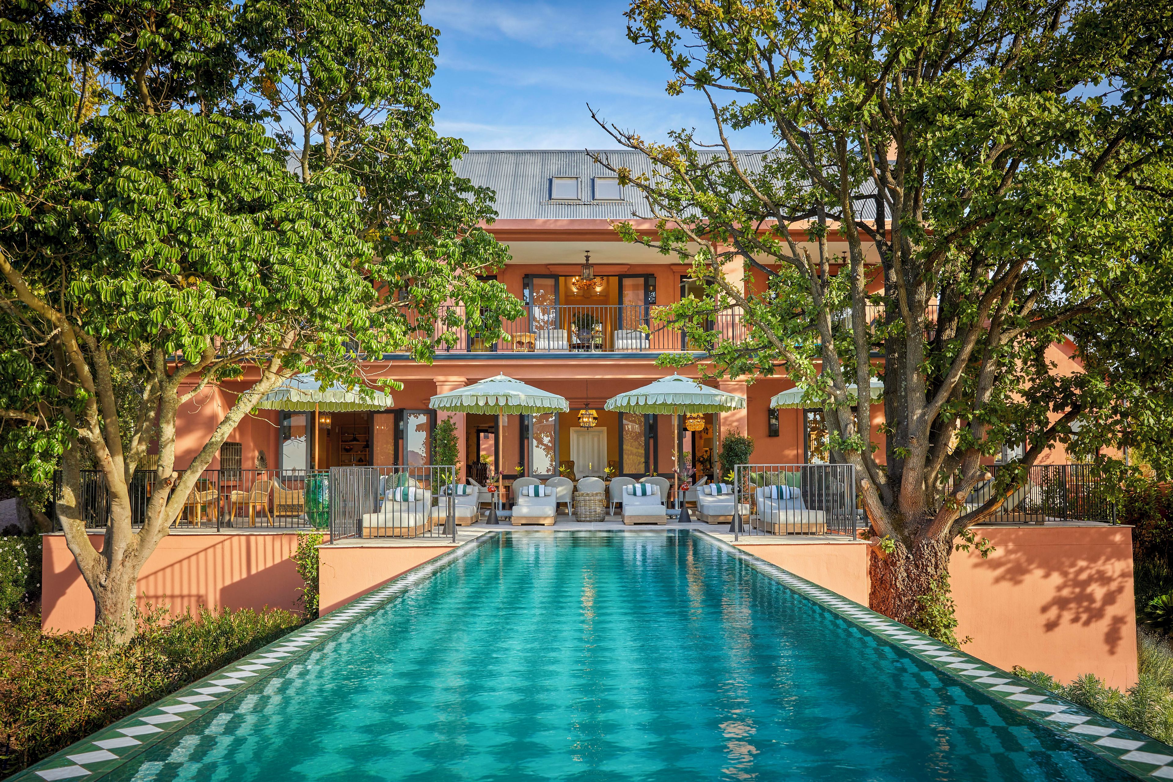 A hotel with a swimming pool, outdoor seating, and a covered patio area.