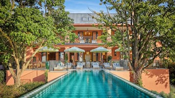 A hotel with a swimming pool, outdoor seating, and a covered patio area.