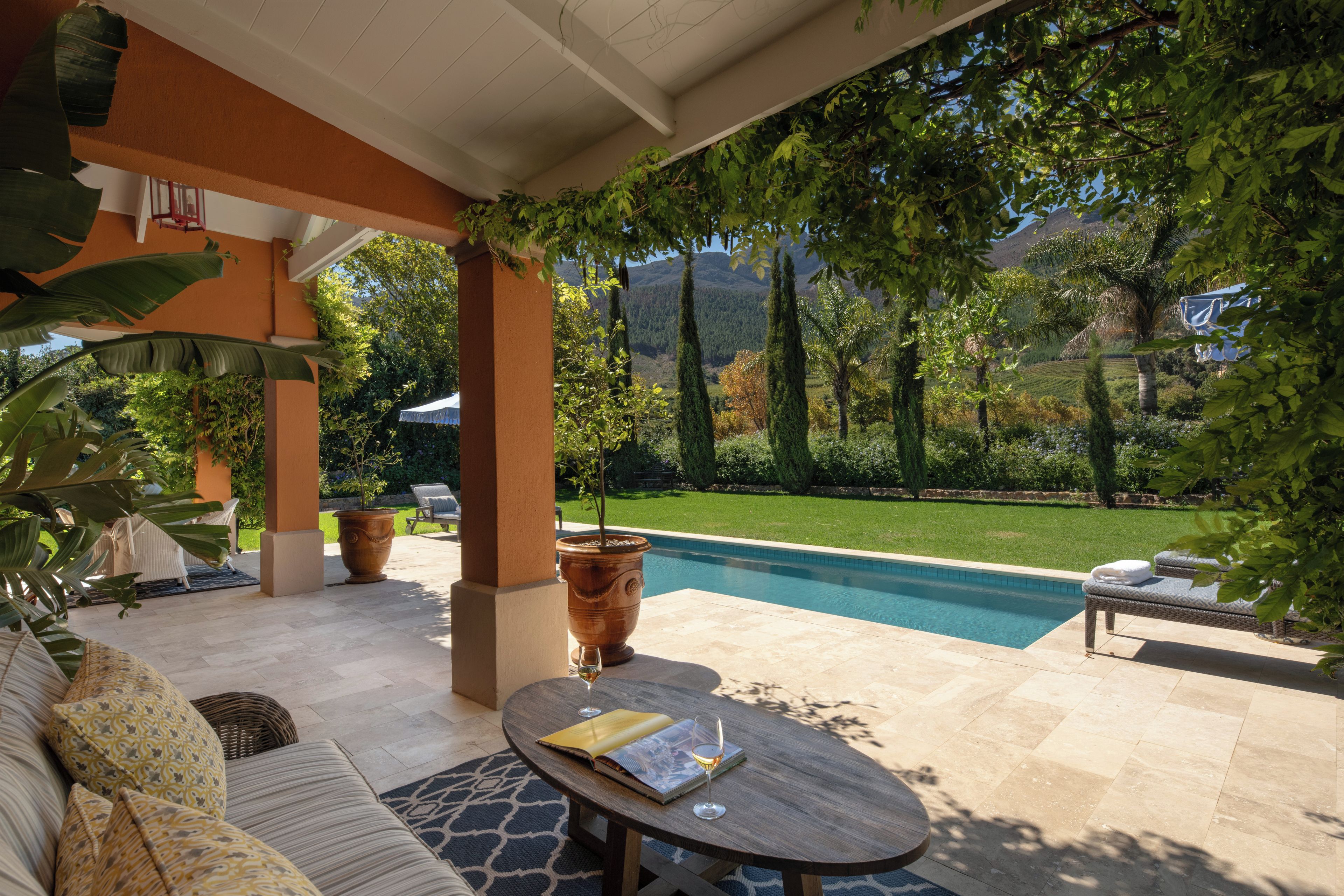 Un patio cubierto con piscina, mobiliario exterior y vistas del paisaje circundante.