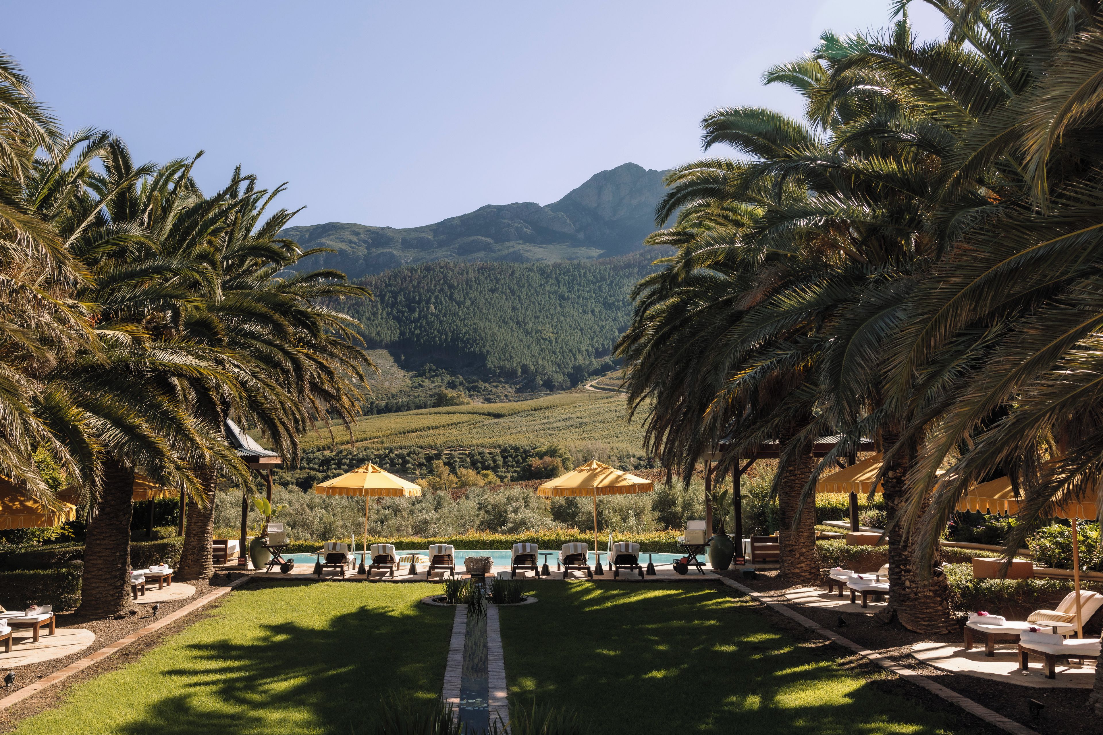 A resort with a pool area, lounge chairs, and umbrellas.