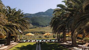 A resort with a pool area, lounge chairs, and umbrellas.