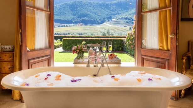 Une baignoire donnant sur un paysage montagneux, avec une porte ouverte.