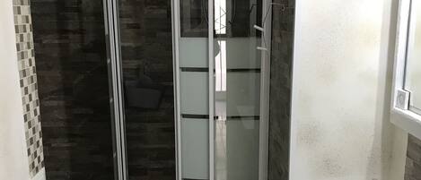 A bathroom with a glass-enclosed shower, a white sink, and a tiled floor.
