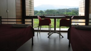 A room with two beds, a table, and two chairs. - HI Ponte de Lima - Pousada de Juventude - Hostel (Ponte de Lima)