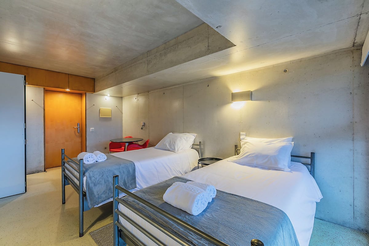 Ein Hotelzimmer mit zwei Betten, einem kleinen Tisch und einem roten Sessel.