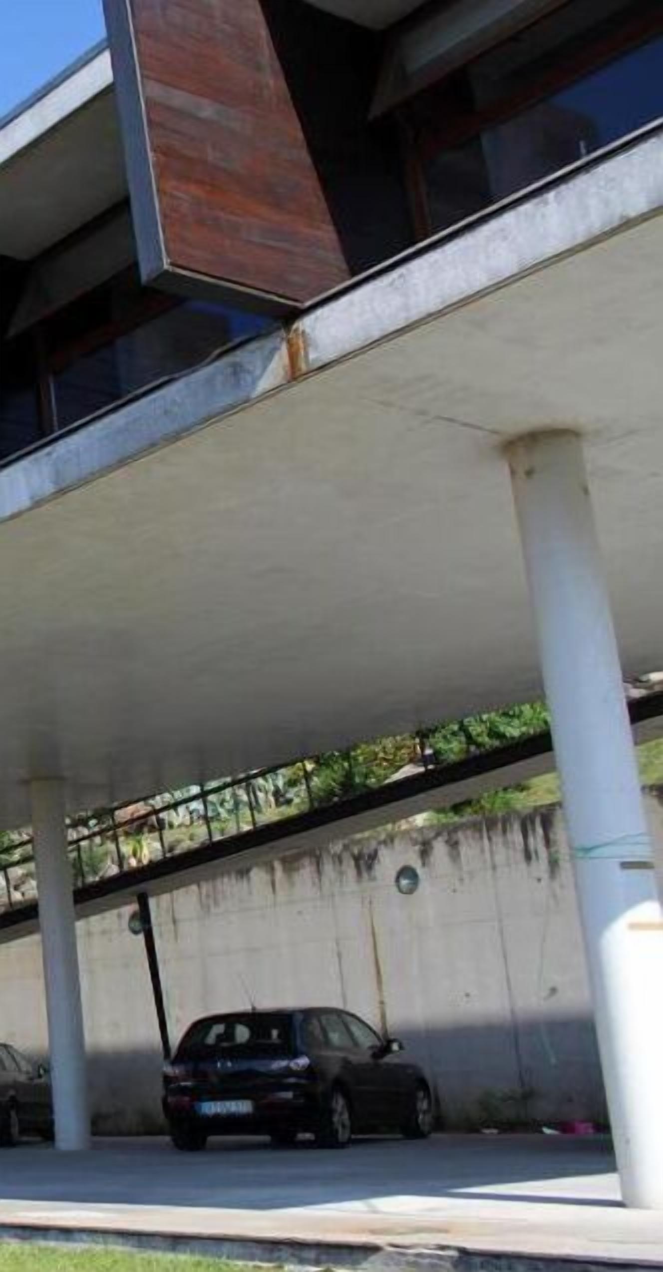 A parking structure with concrete pillars and a car parked underneath.