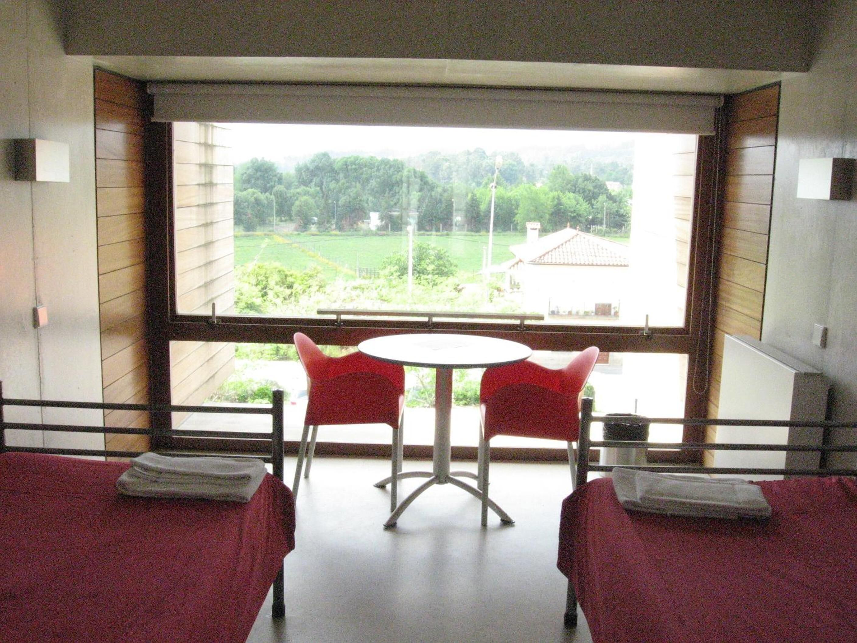A room with two beds, a small table, and two chairs.