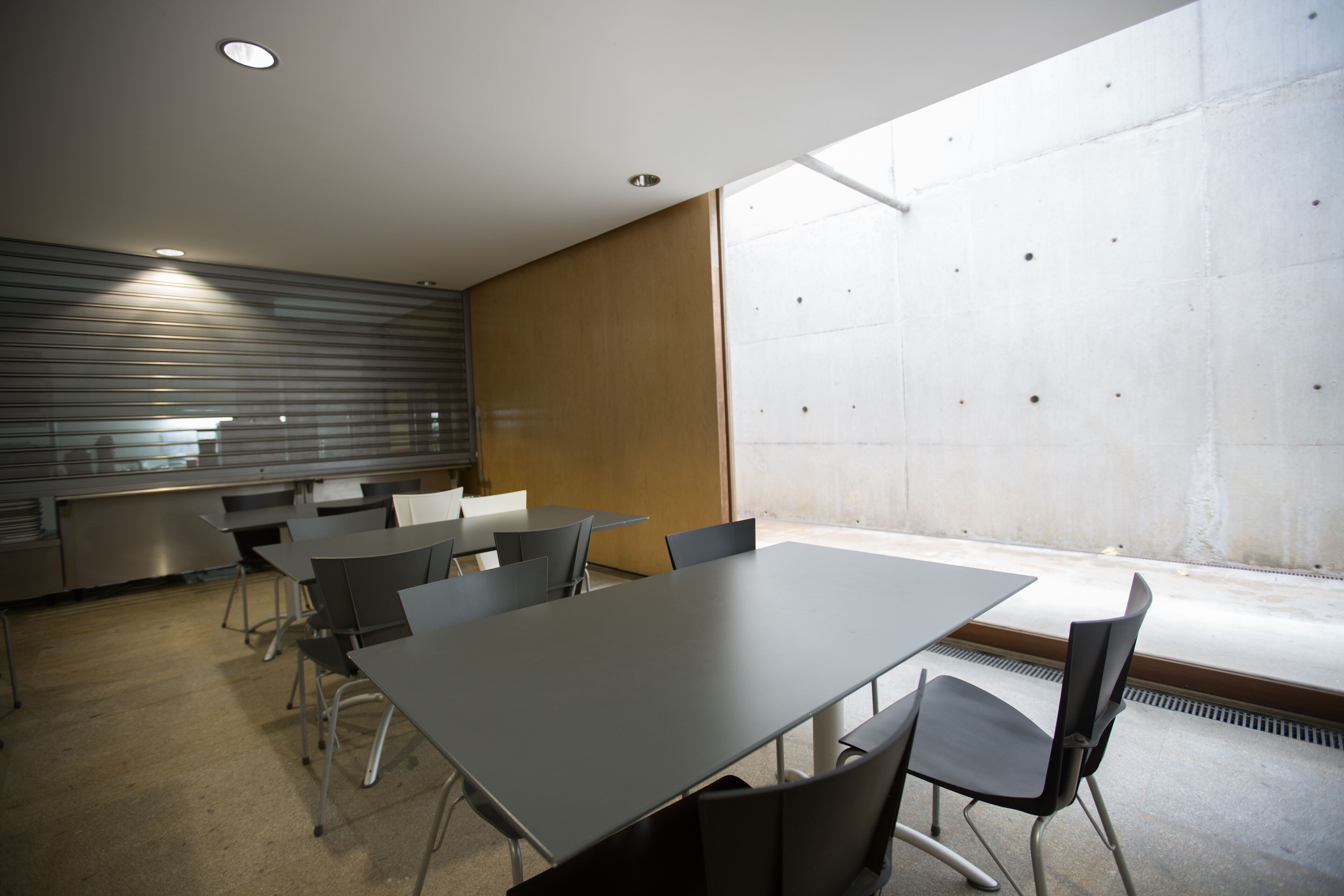 Un salón de conferencias con una larga mesa y sillas, una kitchenette y un ventanal con vistas.
