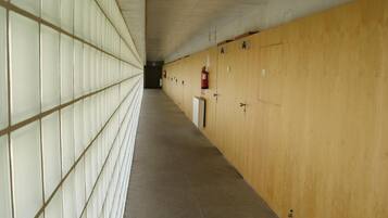 A long corridor with lockers on one side and a fire extinguisher mounted on the wall.