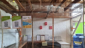 Un espace d’accueil aux murs de verre, avec des instructions pour l’enregistrement des visiteurs et le suivi des contacts, un plafond en bois et un panneau indiquant « HEURE DE DÉPART : 12 h 00 ».