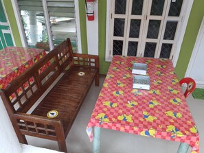Een kamer met een houten bank en twee tafels, bedekt met rode geruit tafelkleden met tekenfilmfiguren.