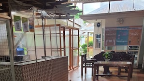 Un espace d’accueil avec un tapis où est inscrit « BIENVENUE », un comptoir avec un plateau en verre, des poubelles de recyclage et un panneau indiquant les « RAPPELS IMPORTANTS POUR LA SÉCURITÉ LIÉS À LA COVID-19 ».