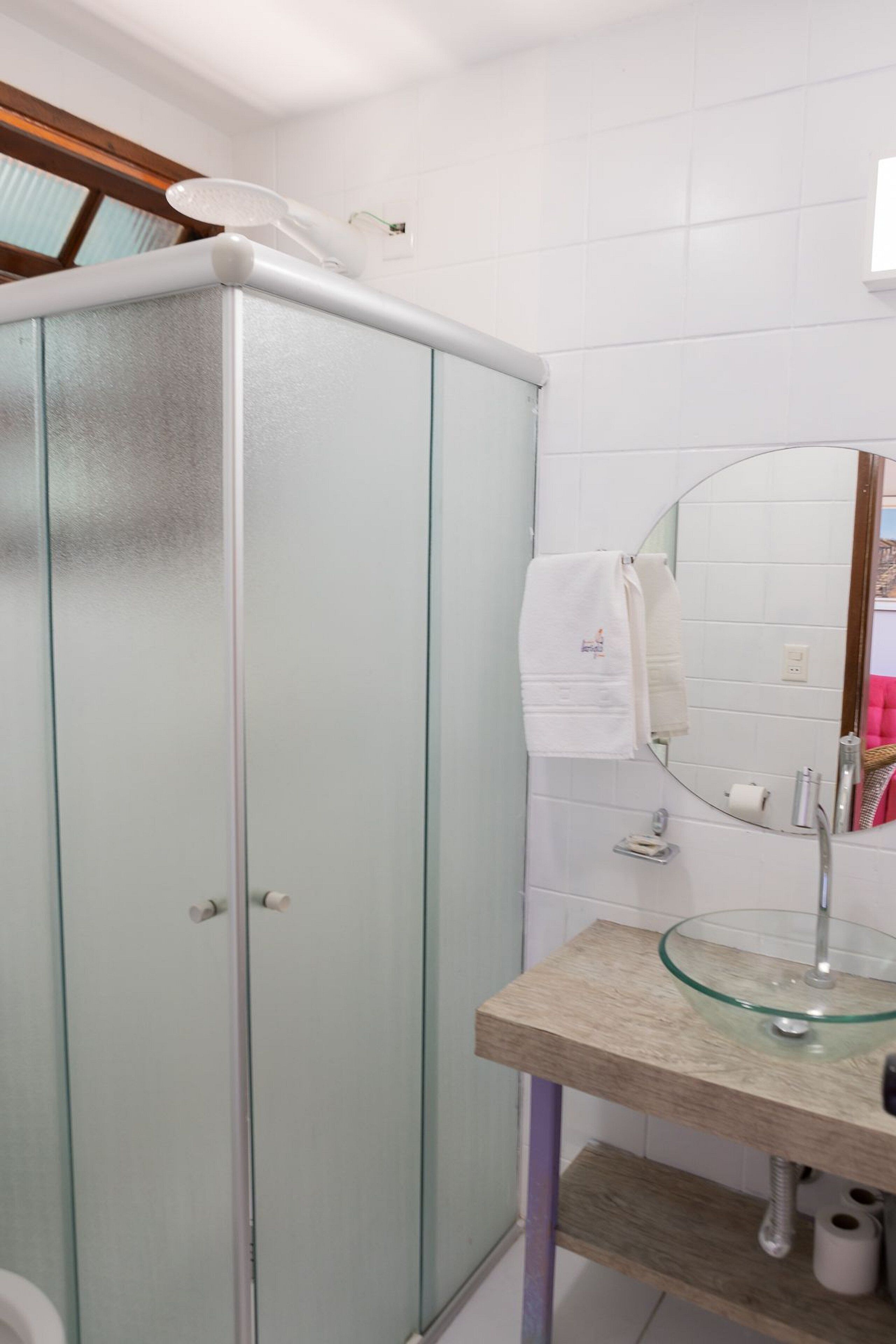 A bathroom with a glass shower enclosure, a glass sink, and a mirror.